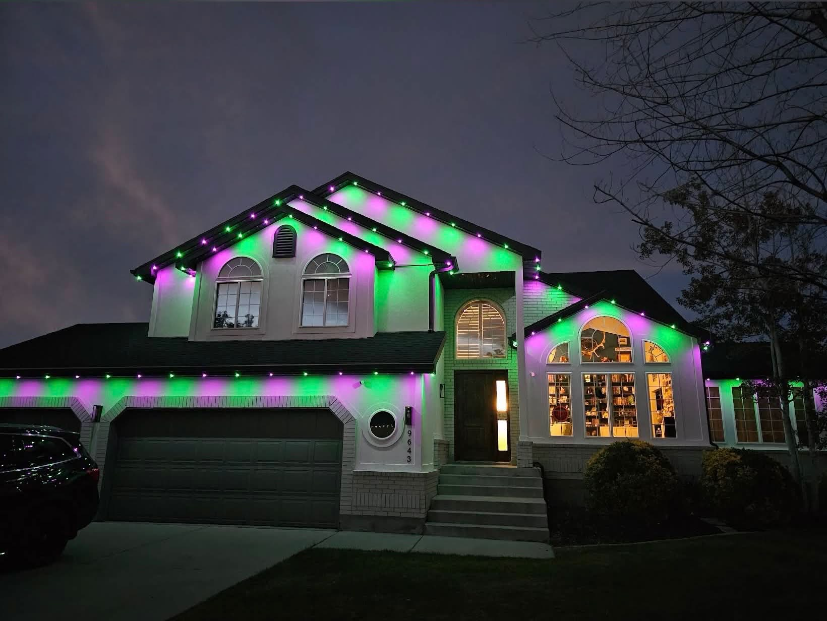 Green and purple roofline lights illuminating a home's peaks