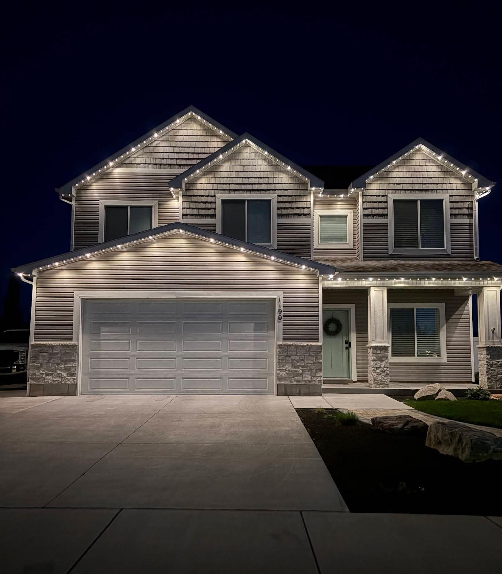 White roofline lights illuminating a two-story home's front and garage